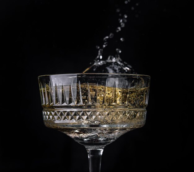 Bicchiere di champagne con splash isolato su sfondo nero