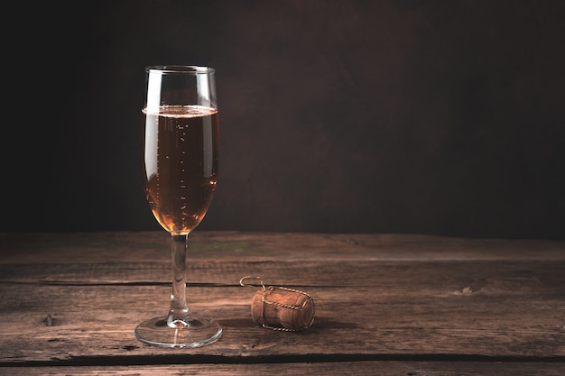 Bicchiere di champagne e un tappo di sughero su un tavolo di legno