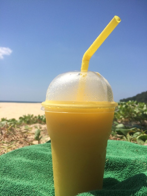 Bicchiere di cocktail con una cannuccia in piedi sulla spiaggia su un asciugamano