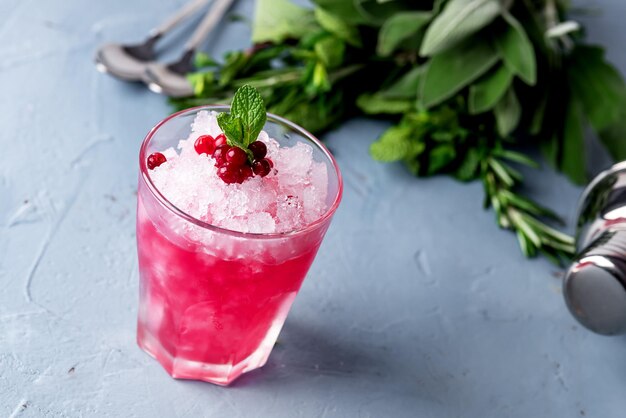 Bicchiere di cocktail freddo con vodka al mirtillo rosso e menta sfondo blu Bevanda estiva orizzontale