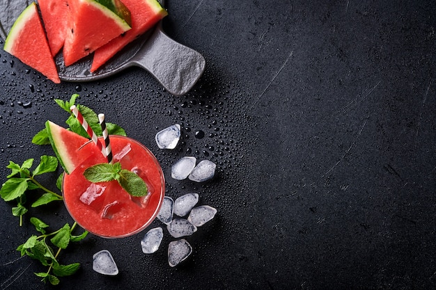 Bicchiere di cocktail Margarita di anguria con menta e ghiaccio. Bevande rinfrescanti estive in bicchieri sul tavolo nero. Concetto di sana alimentazione estiva.