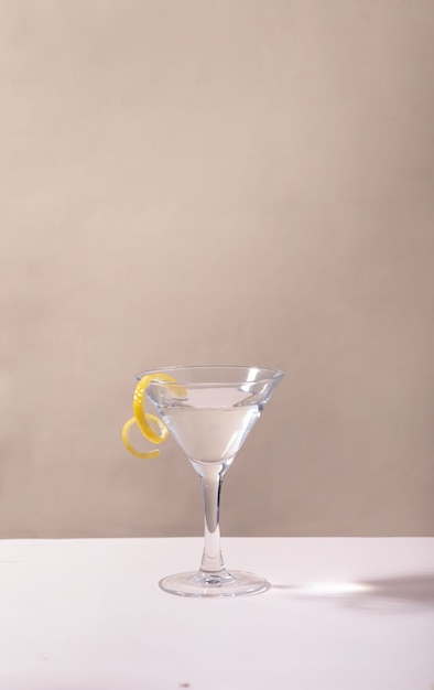 Bicchiere di cocktail martini con goccia di limone sul tavolo su sfondo grigio