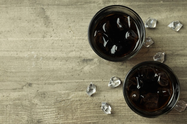 Bicchiere di cola e ghiaccio sul tavolo strutturato grigio.