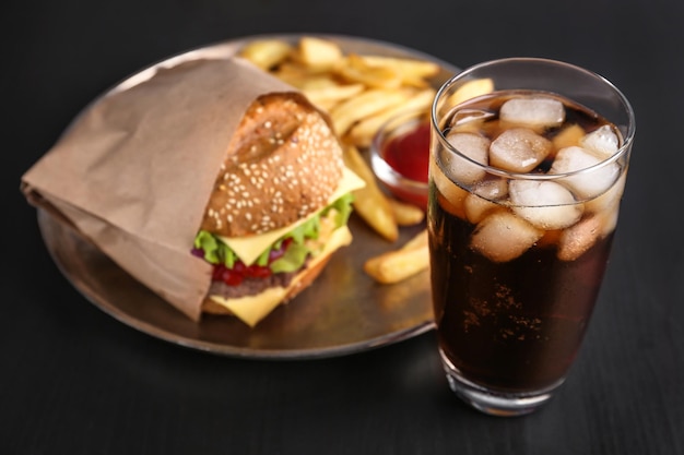 Bicchiere di cola fredda con gustoso hamburger sul tavolo