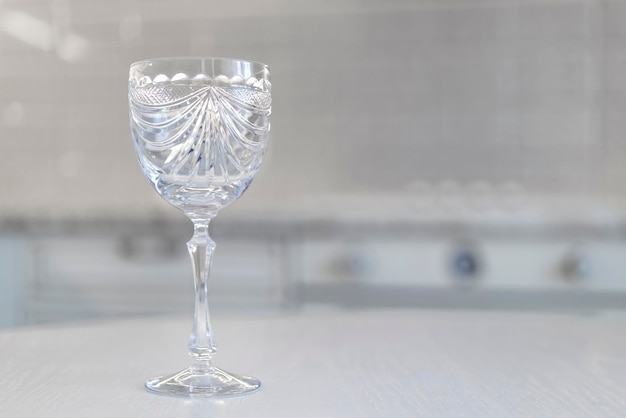 Bicchiere di cristallo vintage con incisione su un gemito bianco sullo sfondo della cucina