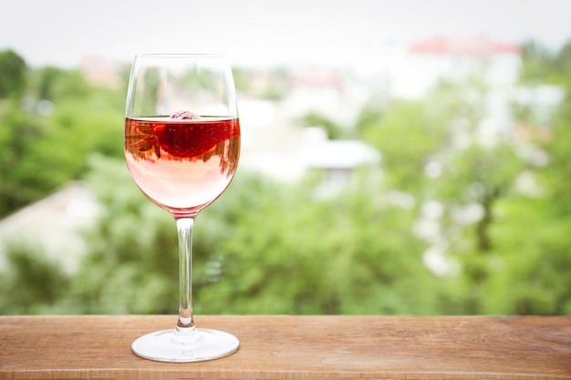 Bicchiere di delizioso vino alla fragola su sfondo sfocato