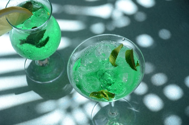 Bicchiere di fata verde da cocktail con limone e foglie di menta Liquore alla menta dolce rinfrescante con ghiaccio e rum di assenzio Cubetti di ghiaccio e Vodka