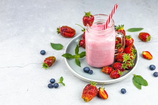 Bicchiere di frappè alla fragola fresca o frullato su sfondo grigio vista dall'alto