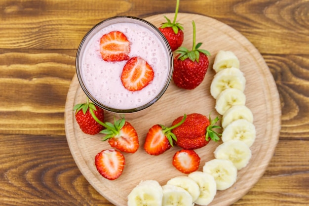 Bicchiere di frullato fresco di fragola e banana su un tavolo di legno Vista dall'alto