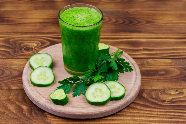 Bicchiere di frullato verde detox di cetriolo e prezzemolo su un tavolo di legno