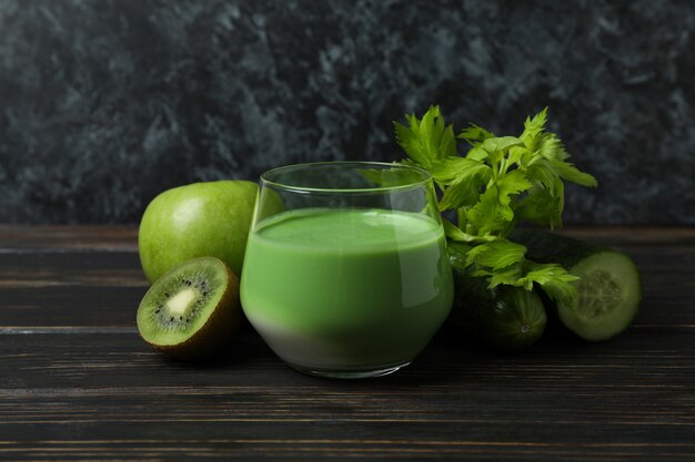 Bicchiere di frullato verde e ingredienti sulla tavola di legno