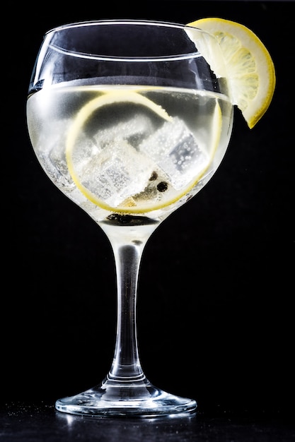 Bicchiere di gin tonic al limone su sfondo nero