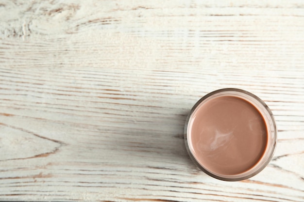 Bicchiere di gustoso latte al cioccolato su sfondo di legno vista dall'alto con spazio per il testo Bevanda a base di latte