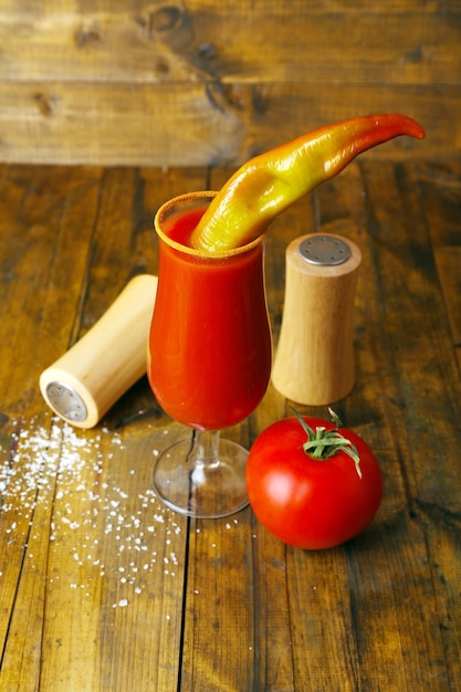 Bicchiere di gustoso succo di pomodoro e pepe sulla tavola di legno