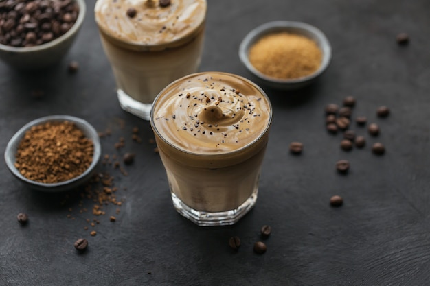 Bicchiere di Iced Dalgona Coffee, un soffice caffè cremoso alla moda e latte su beige chiaro