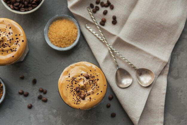 Bicchiere di Iced Dalgona Coffee, un soffice caffè cremoso alla moda e latte su grigio.