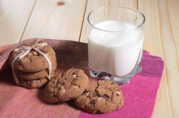 Bicchiere di latte con biscotti al cioccolato per colazione su un tavolo di legno