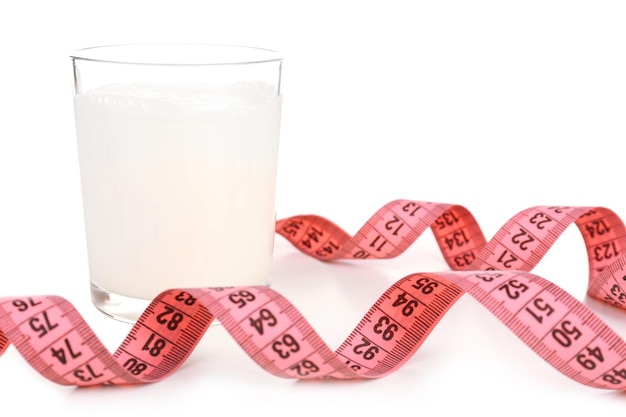 Bicchiere di latte con nastro di misurazione isolato su bianco