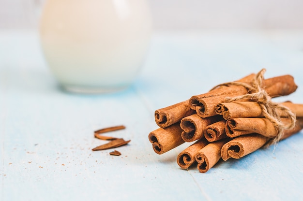 Bicchiere di latte del lanciatore con cannella e tubo del cocktail su fondo di legno blu