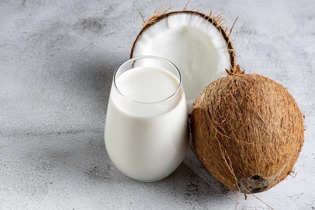 Bicchiere di latte di cocco con pezzi di cocco sul tavolo