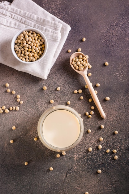 Bicchiere di latte di soia e fagioli di soia sul tavolo Proteine vegetali Vista superiore e verticale