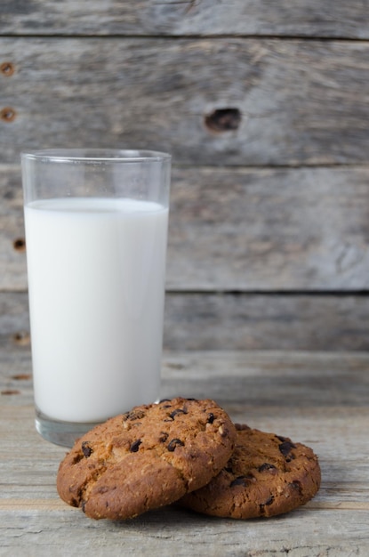 Bicchiere di latte e biscotti con gocce di cioccolato su fondo in legno Colazione del villaggio