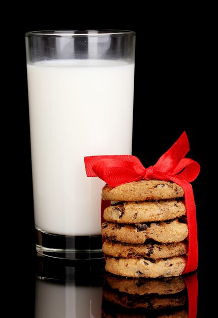 Bicchiere di latte e biscotti isolati su nero