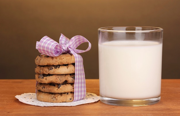 Bicchiere di latte e biscotti sulla tavola di legno su fondo marrone