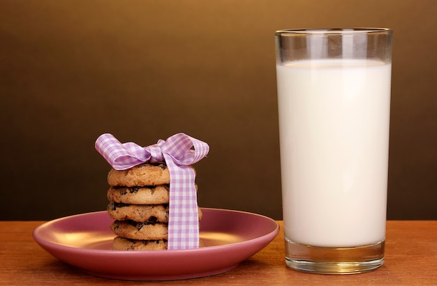 Bicchiere di latte e biscotti sulla tavola di legno sulla superficie marrone