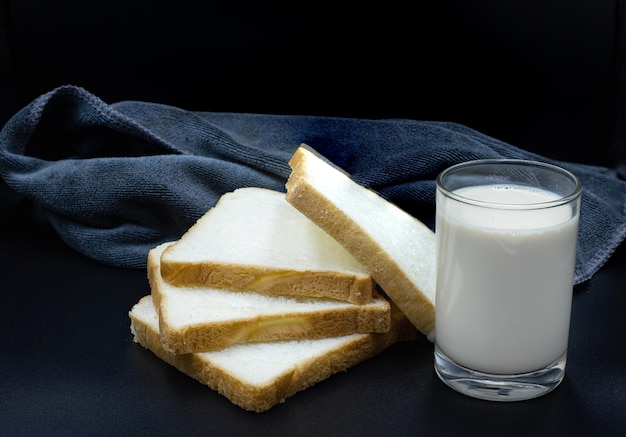 Bicchiere di latte e pane a fette per colazione su sfondo nero immagine di cibo e concetto sano