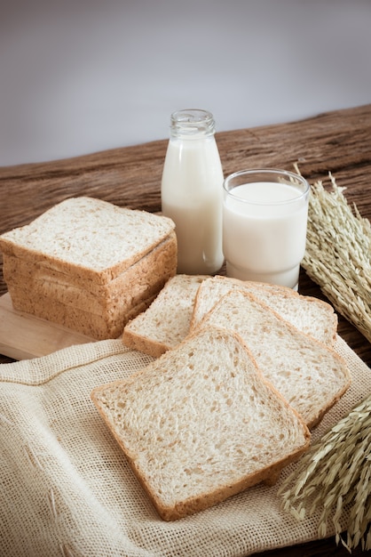 Bicchiere di latte e pane integrale sul bordo di legno