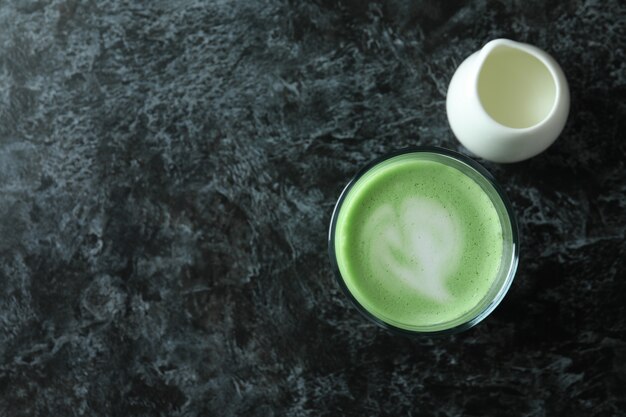 Bicchiere di latte matcha e latte su sfondo nero affumicato