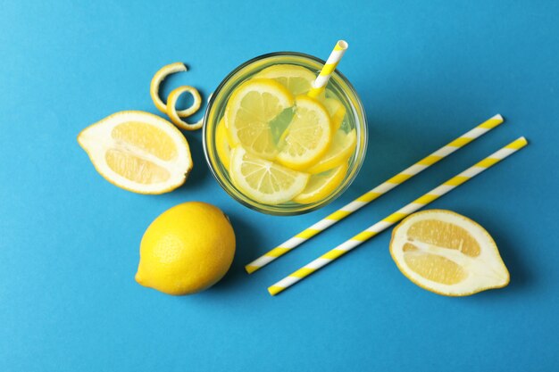 Bicchiere di limonata, cannucce e limoni su sfondo blu