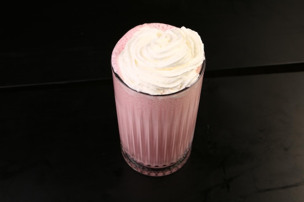 Bicchiere di milkshake al lampone con panna montata e lamponi freschi