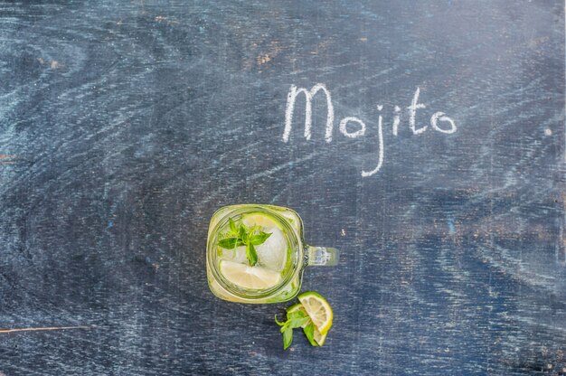 Bicchiere di mojito con il primo piano del cubo di ghiaccio di menta e lime sulla superficie di legno scuro