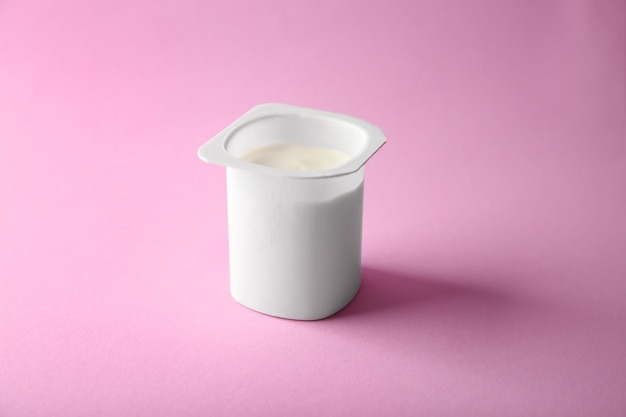 Bicchiere di plastica con yogurt squisito su sfondo colorato