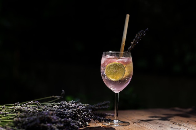 Bicchiere di rosa cocktail bouquet di lavanda su tavola di legno su sfondo nero