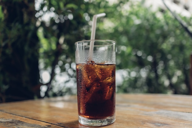 Bicchiere di soda con una cannuccia bianca sul tavolo.