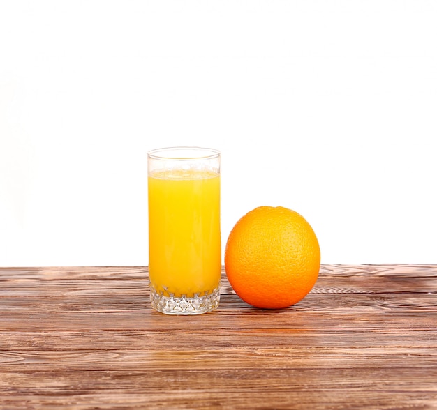 Bicchiere di succo d'arancia appena spremuto con metà arancia affettata sul tavolo di legno