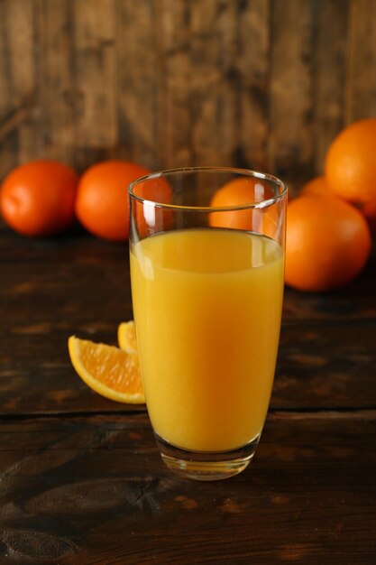 Bicchiere di succo d'arancia con le fette sul fondo della tavola in legno