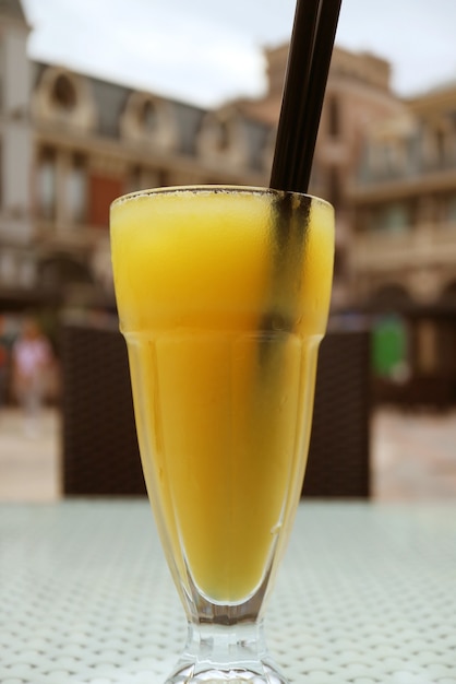 Bicchiere di succo d'arancia freddo sul tavolo della terrazza all'aperto