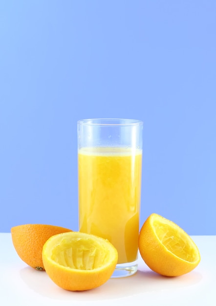 Bicchiere di succo d'arancia fresco con fetta da spremere su sfondo blu..