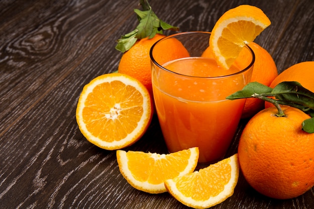 Bicchiere di succo d&#39;arancia fresco e arance su fondo in legno