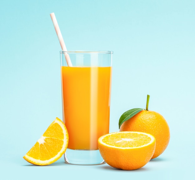 Bicchiere di succo d'arancia fresco sul tavolo di legno, frutta fresca Succo d'arancia in vetro con un gruppo di arancia sulla parete blu, messa a fuoco selettiva sul vetro