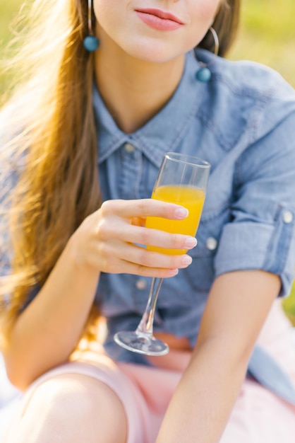 Bicchiere di succo d'arancia nella mano di una giovane donna