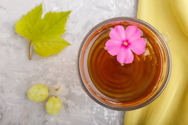 Bicchiere di succo d'uva verde con tessuto verde e fiore rosa. Vista dall'alto