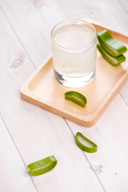 Bicchiere di succo di aloe vera con foglie fresche su un tavolo di legno