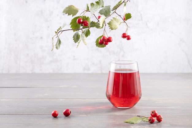 bicchiere di succo di bacche di biancospino e un ramo con frutti di bosco freschi