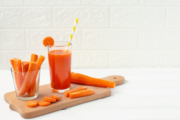 Bicchiere di succo di carota e carota fresca sul tagliere