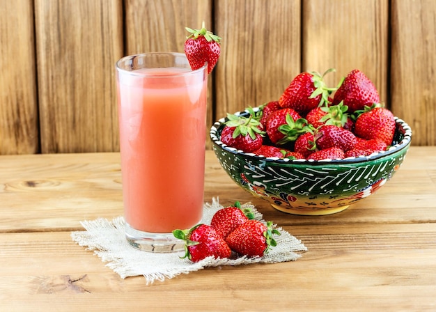 Bicchiere di succo di fragola con fragole fresche sul tavolo